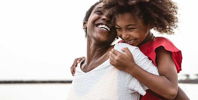 Black mother with daughter on her shoulders smiling at each other