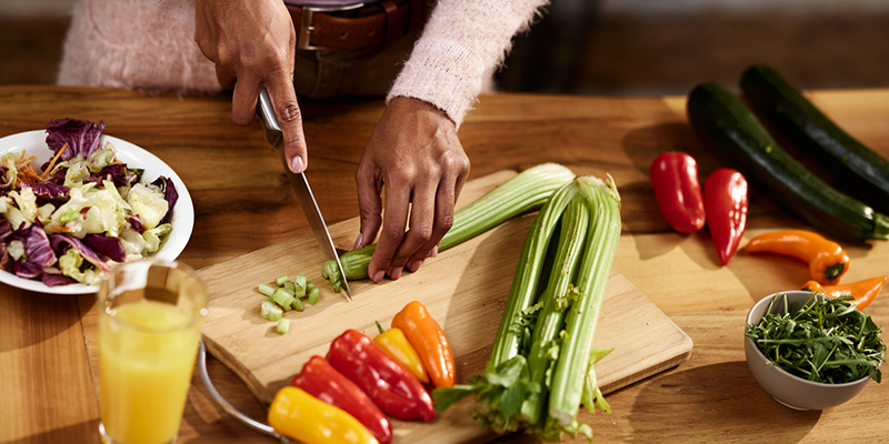 Black woman cutting up celery on a cutting board