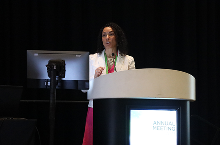 Tossa presents at podium of AACR session