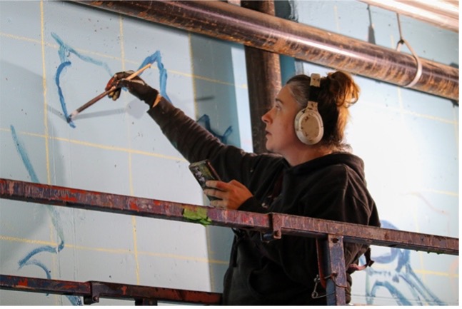 Artist Nico Cathcart painting a large-scale mural