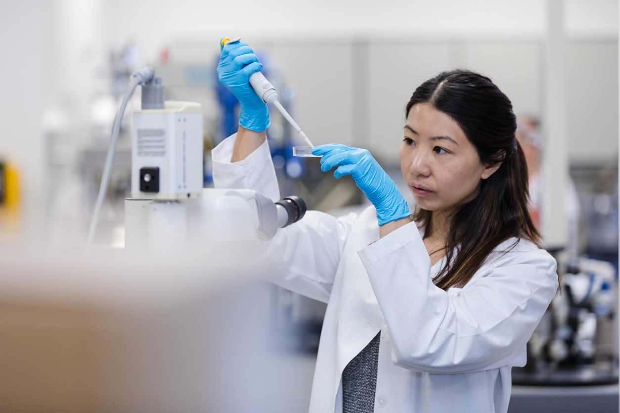 The mid adult female doctoral student conducts experiments using a syringe and petri dish in the university laboratory.