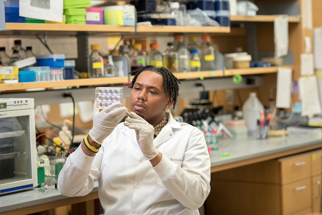 Bryan McKiver examines equipment while seated in a lab.